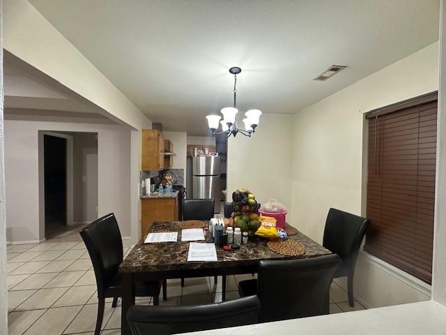 dining room with light tile patterned floors, visible vents, and a chandelier