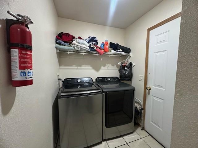 clothes washing area with laundry area, washing machine and dryer, and light tile patterned flooring