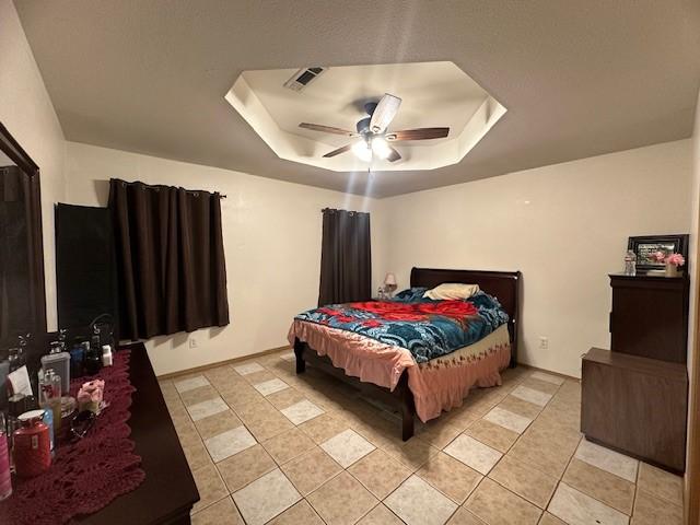 bedroom featuring ceiling fan, a tray ceiling, and visible vents