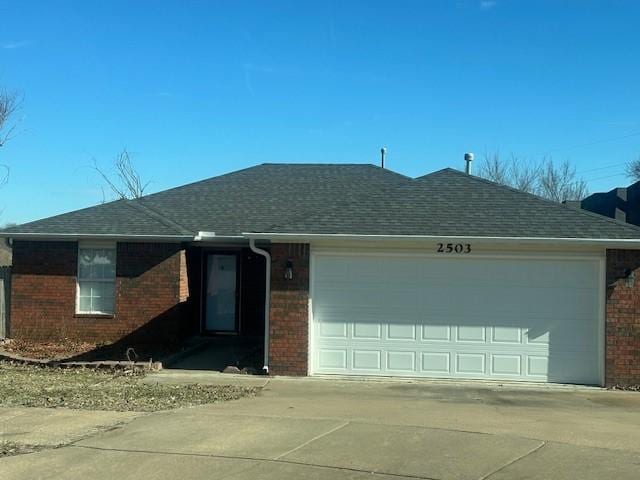 ranch-style home featuring a garage, concrete driveway, brick siding, and roof with shingles