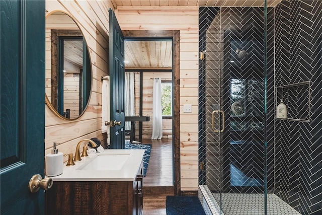 full bathroom with wood walls, wood finished floors, vanity, and a stall shower