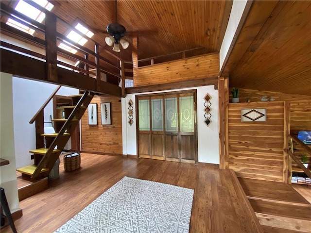 interior space with a ceiling fan, wood ceiling, wood walls, and wood finished floors