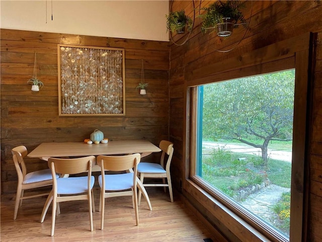 dining area with light wood-style flooring and wooden walls