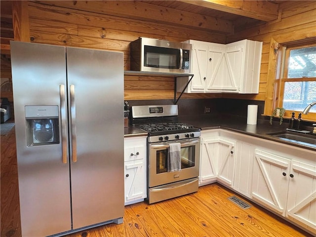 kitchen featuring dark countertops, white cabinetry, stainless steel appliances, and a sink