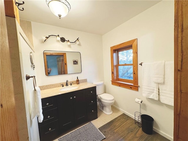 bathroom with toilet, wood finished floors, vanity, and baseboards