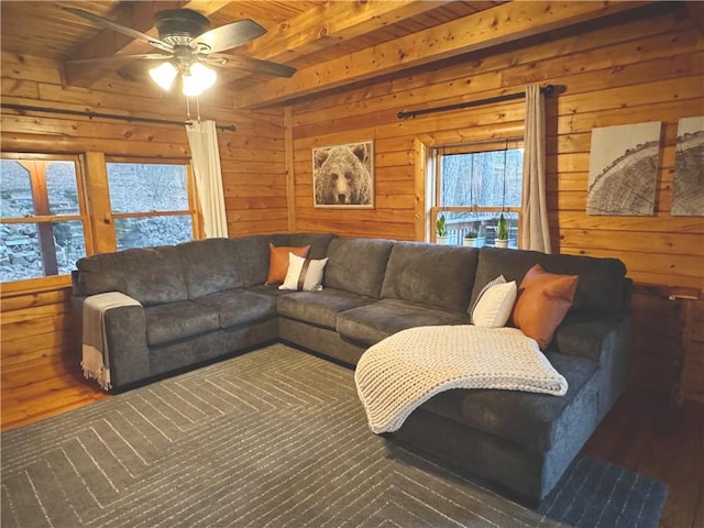 living room with beam ceiling, wooden ceiling, wood walls, and ceiling fan