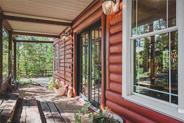 exterior space with a porch, fence, and log siding