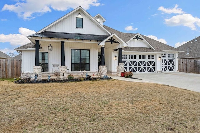 view of front of house featuring driveway, a standing seam roof, covered porch, fence, and a front yard