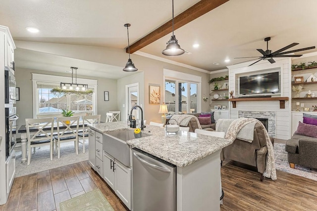 kitchen with a fireplace, open floor plan, white cabinets, a sink, and an island with sink