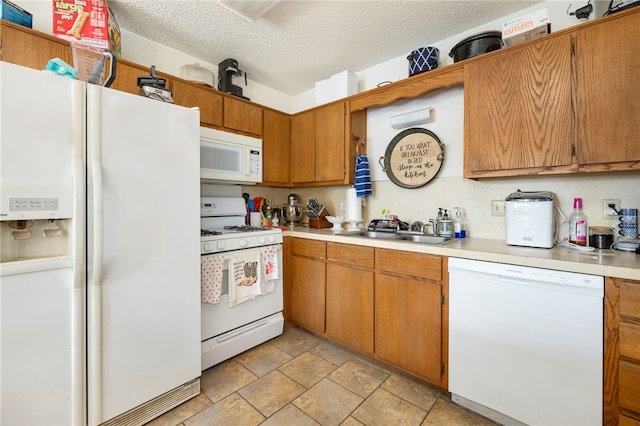 kitchen with light countertops, white appliances, brown cabinetry, and a sink