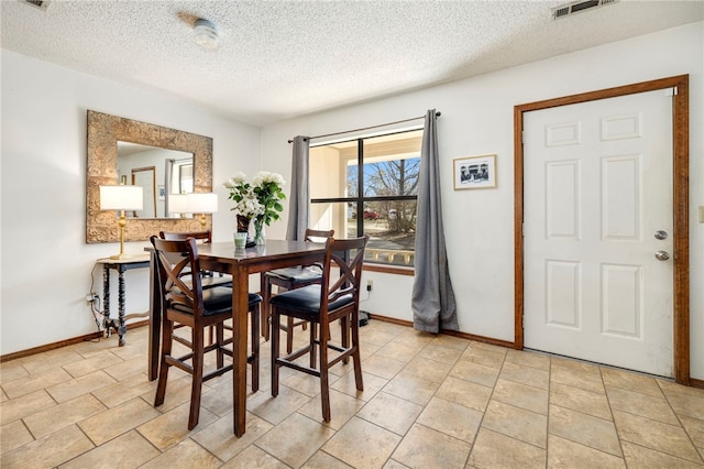 dining room featuring visible vents, a textured ceiling, and baseboards