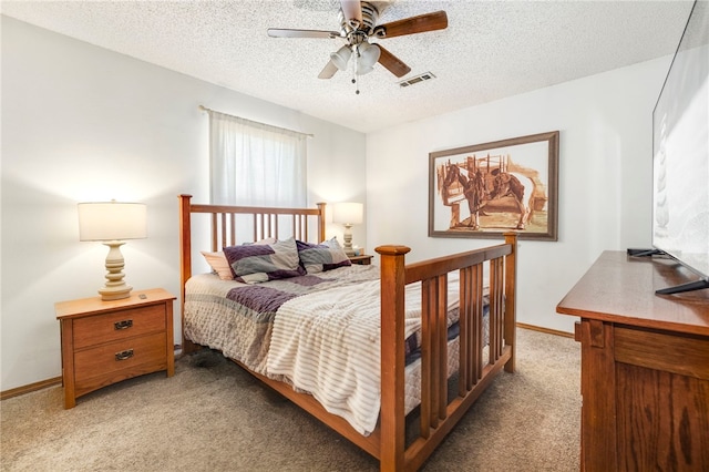 bedroom with a textured ceiling, carpet flooring, a ceiling fan, visible vents, and baseboards