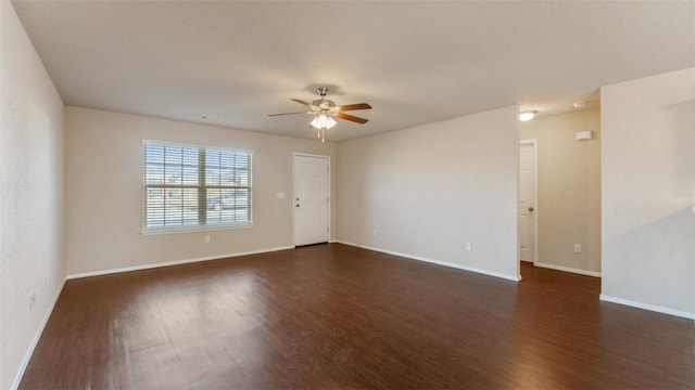 spare room featuring dark wood-style floors, ceiling fan, and baseboards