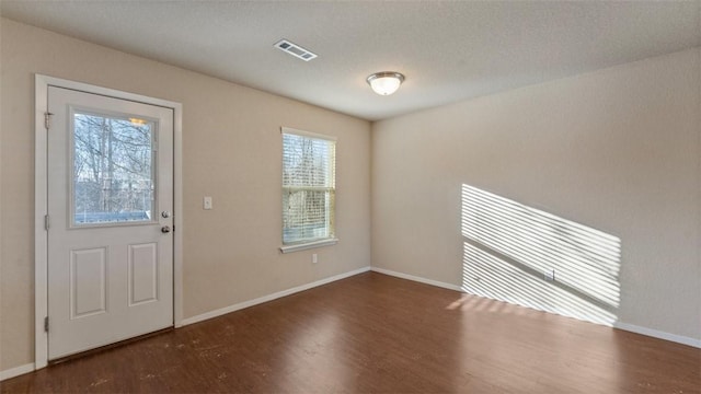 interior space featuring dark wood-style floors, visible vents, and baseboards