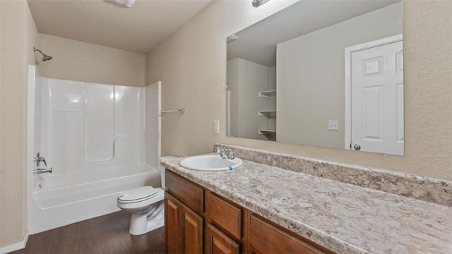 bathroom featuring a textured wall, toilet, wood finished floors, vanity, and shower / bathing tub combination