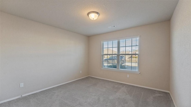 empty room featuring light carpet, baseboards, visible vents, and a textured ceiling