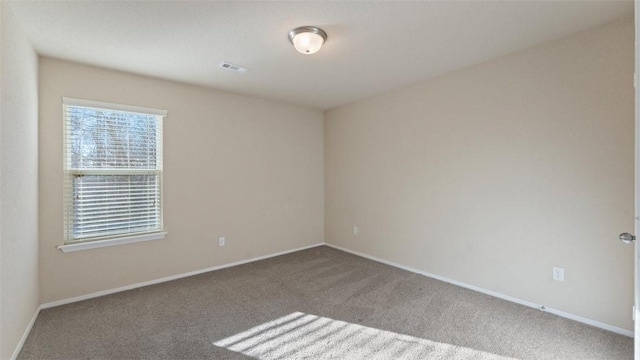 unfurnished room featuring carpet floors, visible vents, and baseboards