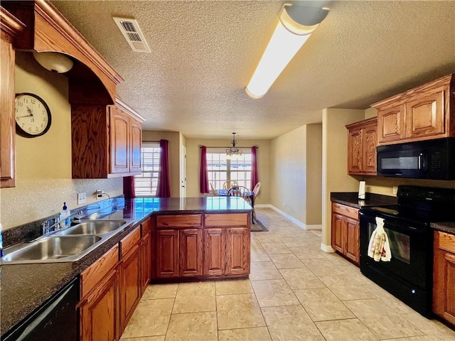 kitchen featuring visible vents, a peninsula, a sink, black appliances, and dark countertops