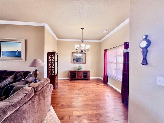 living area featuring baseboards, light wood-style floors, ornamental molding, and a textured ceiling