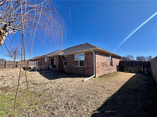 rear view of property featuring brick siding and a fenced backyard