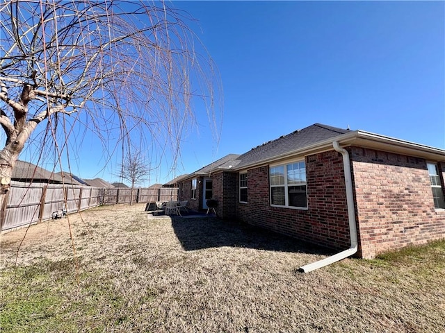 view of side of home featuring brick siding and a fenced backyard