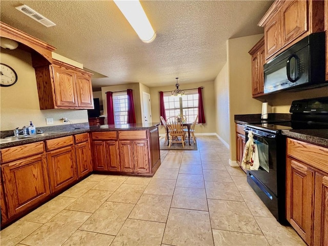 kitchen featuring brown cabinetry, visible vents, a peninsula, black appliances, and dark countertops