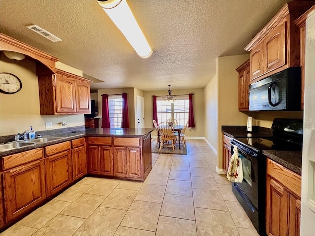 kitchen featuring visible vents, a peninsula, black appliances, dark countertops, and brown cabinets