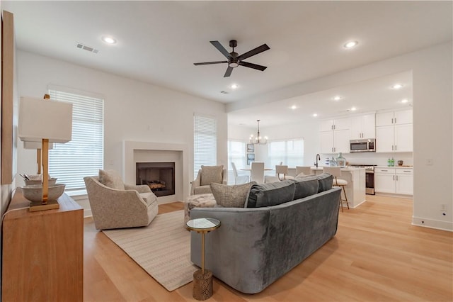 living area with recessed lighting, visible vents, light wood-style flooring, and ceiling fan with notable chandelier