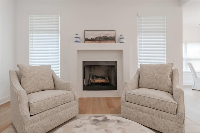 living area with light wood-type flooring, a fireplace, and baseboards