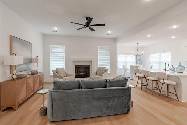 living area featuring ceiling fan with notable chandelier, recessed lighting, a fireplace, and light wood-style floors