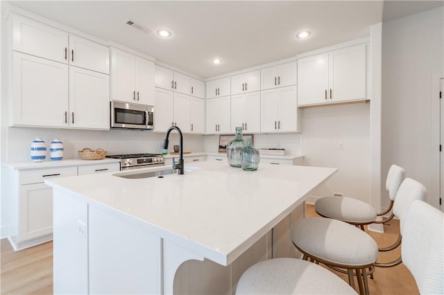 kitchen with an island with sink, stainless steel appliances, and light countertops