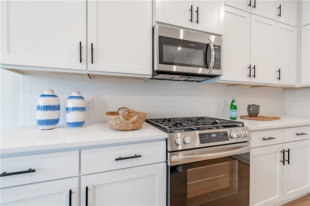 kitchen featuring appliances with stainless steel finishes, light countertops, decorative backsplash, and white cabinetry