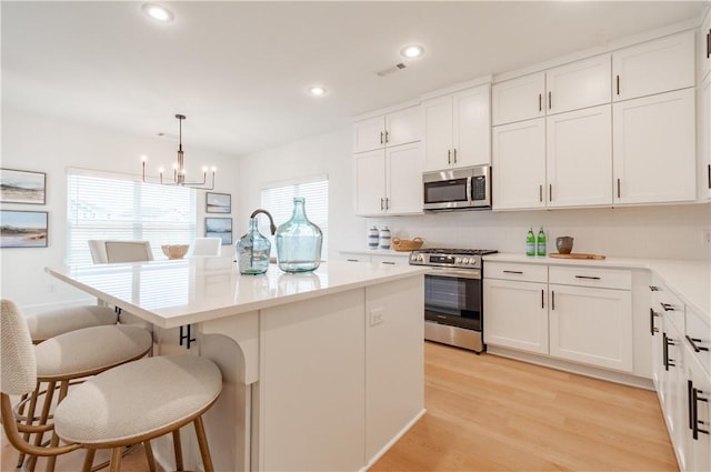 kitchen with white cabinetry, light countertops, appliances with stainless steel finishes, a center island, and pendant lighting