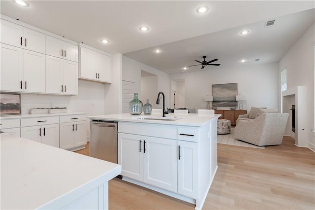 kitchen featuring white cabinets, an island with sink, a sink, light countertops, and stainless steel dishwasher