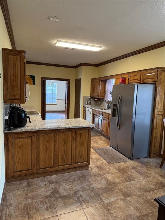 kitchen featuring a textured ceiling, a peninsula, stainless steel fridge with ice dispenser, ornamental molding, and brown cabinets