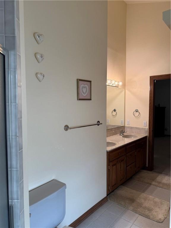 bathroom featuring baseboards, double vanity, a sink, and tile patterned floors