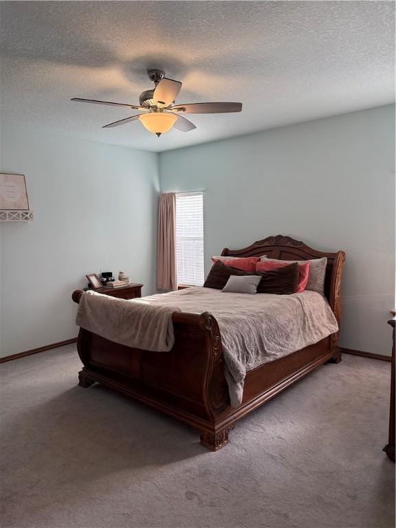 carpeted bedroom featuring ceiling fan, baseboards, and a textured ceiling