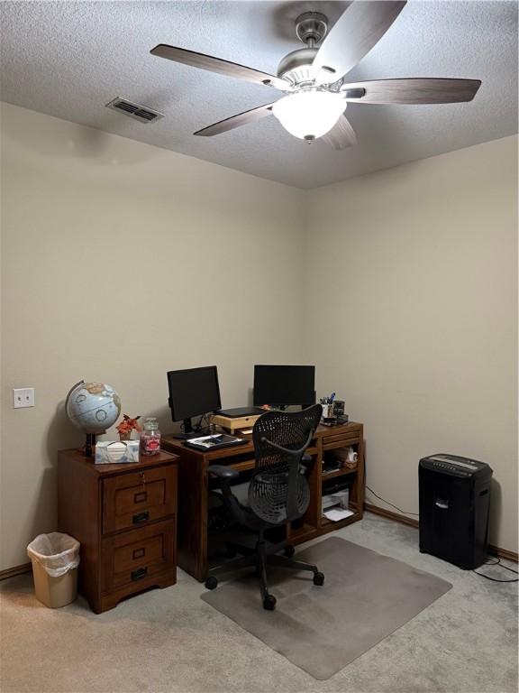 office space with light carpet, a ceiling fan, visible vents, and a textured ceiling