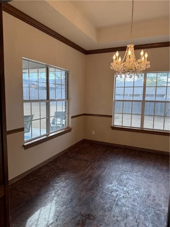 spare room featuring a chandelier, plenty of natural light, and baseboards