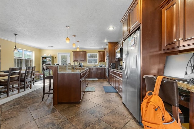 kitchen with a kitchen island with sink, a breakfast bar area, stainless steel appliances, and decorative light fixtures