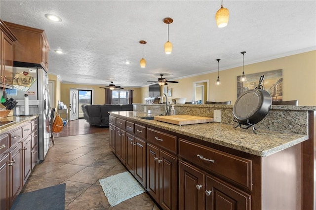 kitchen featuring ornamental molding, pendant lighting, a sink, and open floor plan