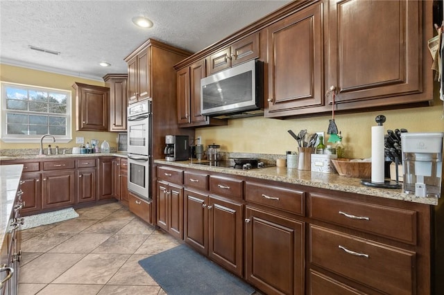 kitchen featuring stainless steel appliances, visible vents, a textured ceiling, and light stone countertops