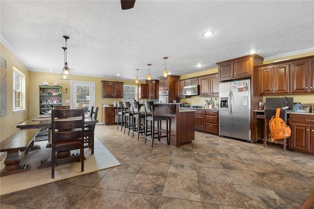 kitchen with appliances with stainless steel finishes, a kitchen island, a breakfast bar, and pendant lighting