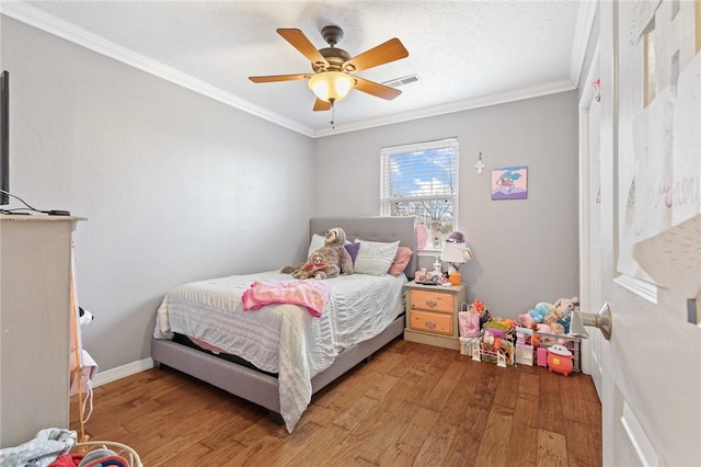 bedroom featuring a ceiling fan, baseboards, visible vents, light wood-type flooring, and crown molding