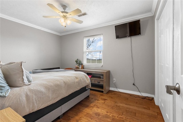 bedroom with crown molding, visible vents, ceiling fan, wood finished floors, and baseboards