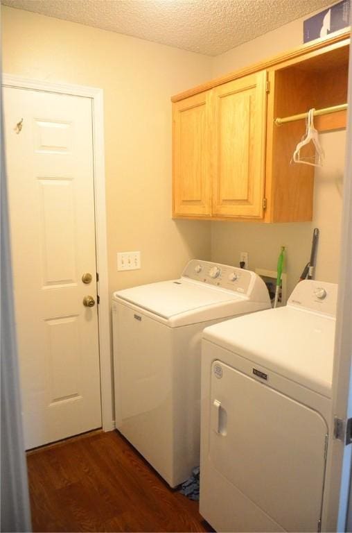 laundry area featuring a textured ceiling, dark wood-style flooring, washer and clothes dryer, and cabinet space