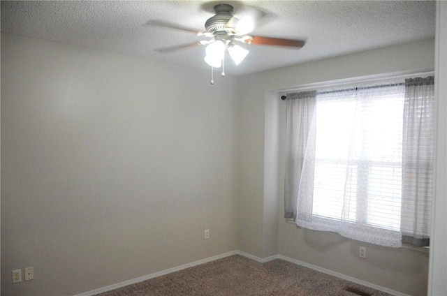 spare room featuring carpet, visible vents, a textured ceiling, and baseboards