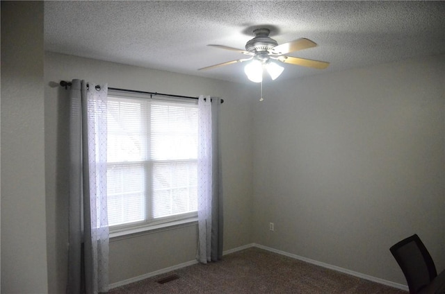 empty room with a textured ceiling, a ceiling fan, visible vents, and baseboards