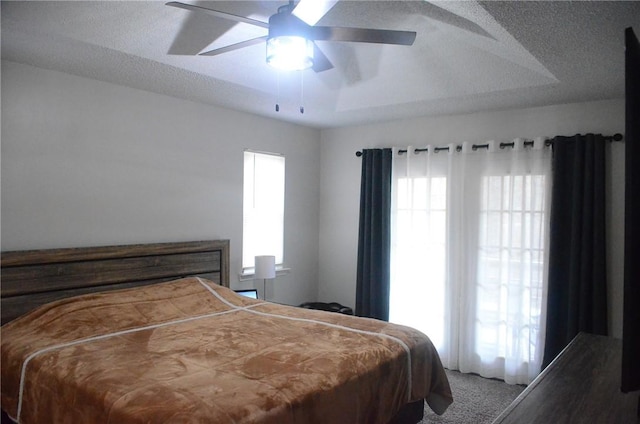 bedroom featuring a ceiling fan, a raised ceiling, a textured ceiling, and carpet flooring