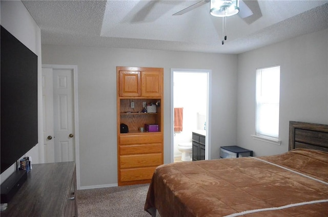 carpeted bedroom with a textured ceiling, baseboards, and ensuite bathroom